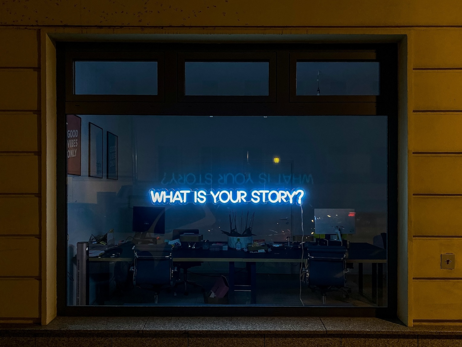 Neonový nápis na okně "What is your story"