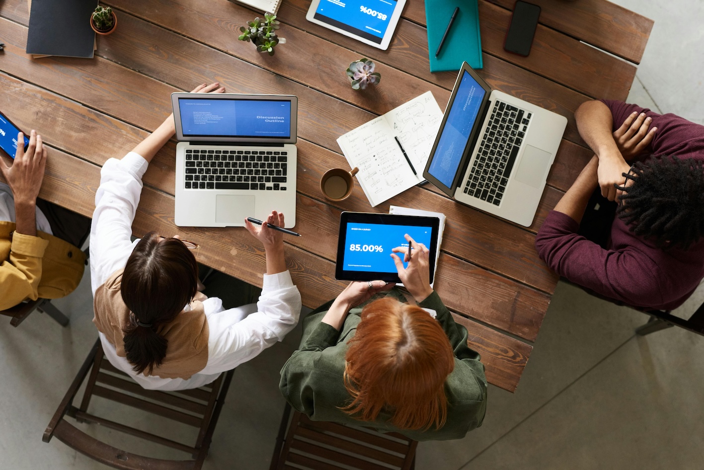  A team of professionals sitting together at a table with laptops, likely brainstorming or working on a project.